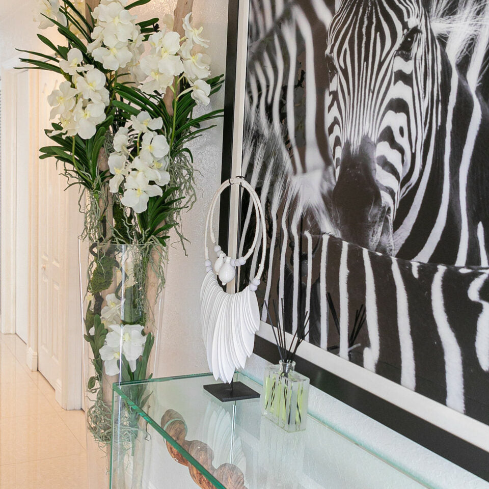 White Vanda orchids and floating wood inside a large conical glass vase.