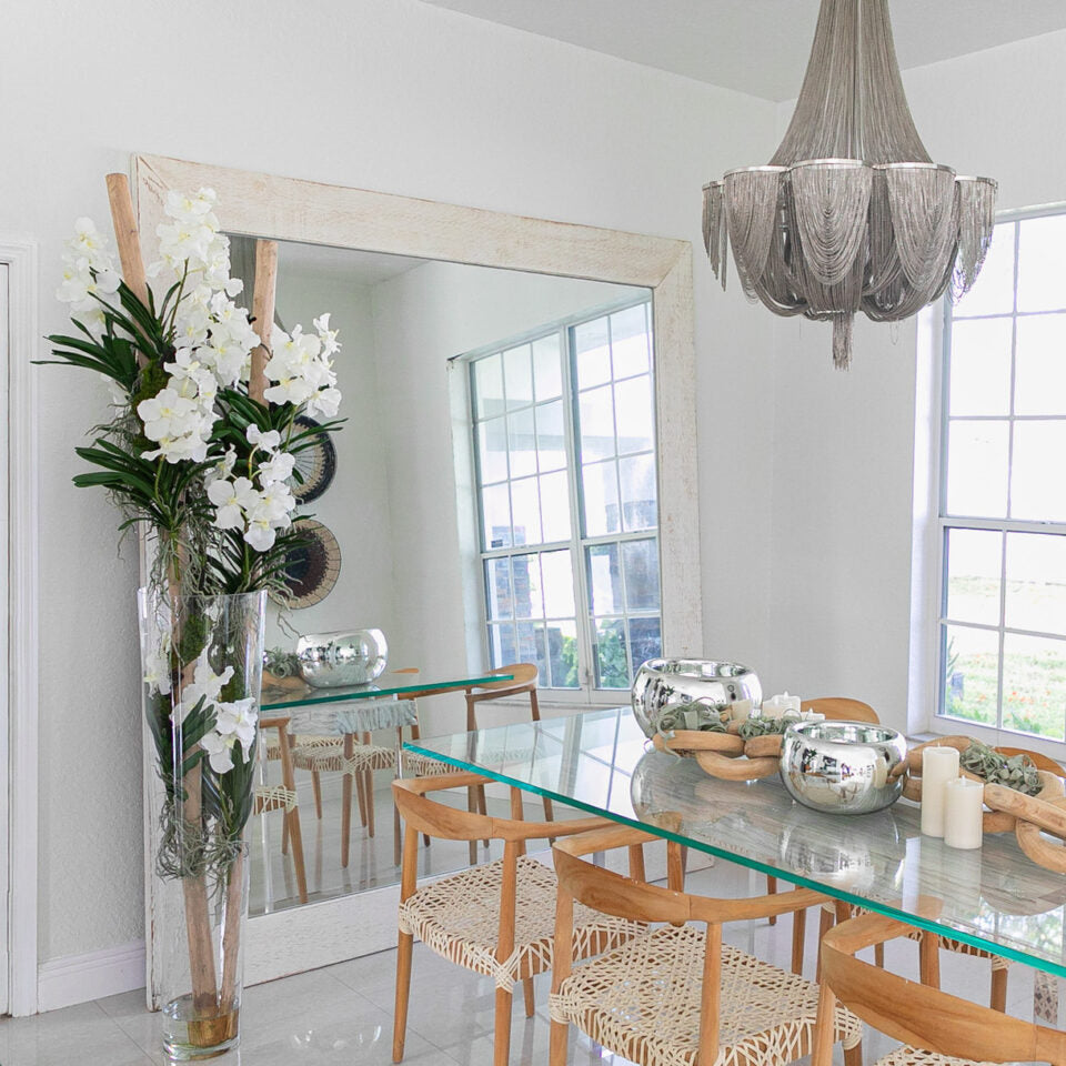 White Vanda orchids and floating wood inside a large conical glass vase.