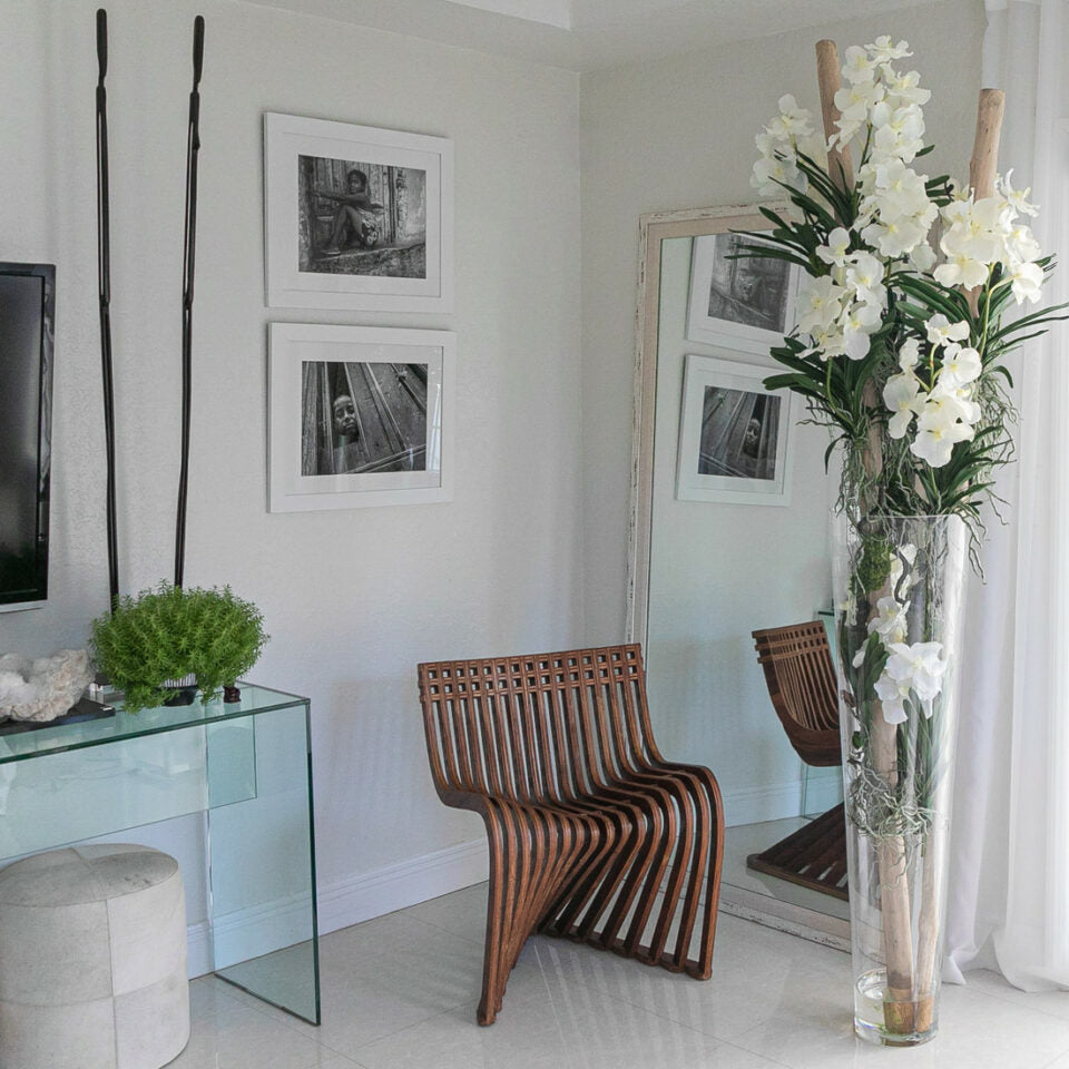 White Vanda orchids and floating wood inside a large conical glass vase.